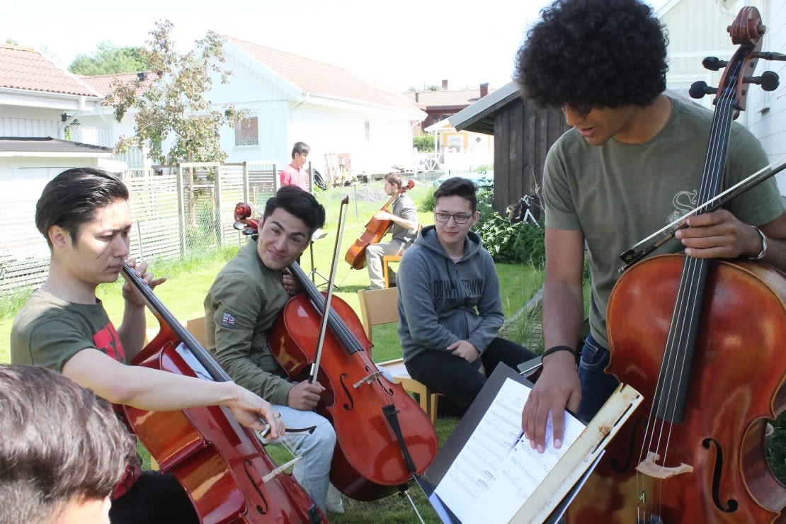 Mostafa Kazemi, en el centro, sonríe durante un ensayo de la sección de violonchelo. Nunca había tocado un instrumento antes de unirse a la Dream Orchestra.