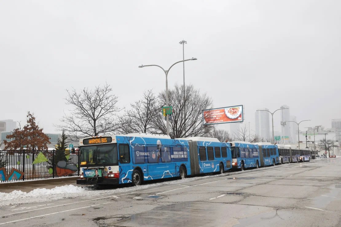 Los autobuses calefactores de la Autoridad de Tránsito de Chicago se encuentran en la zona de aterrizaje de migrantes durante temperaturas frías extremas el viernes. Kamil Krzaczynski/AFP vía Getty Images