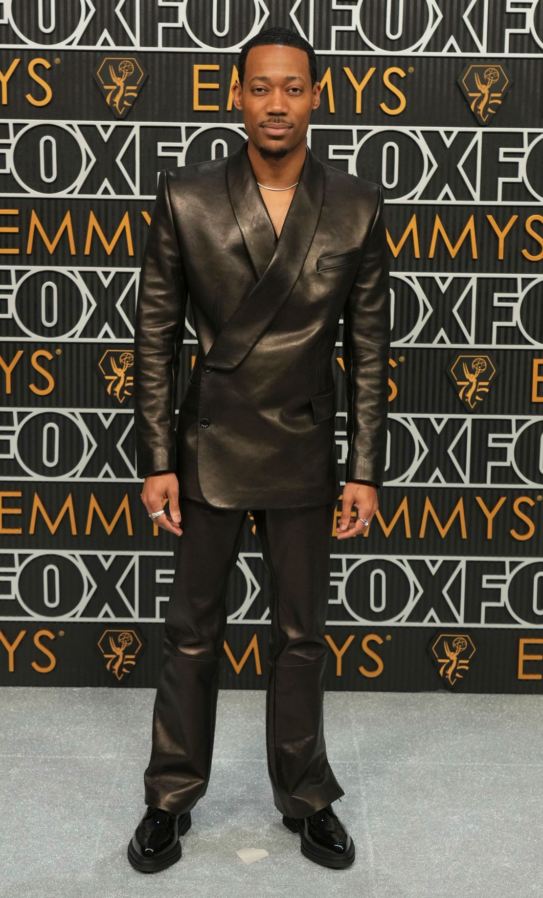 Tyler James Williams, de Abbott Elementary, lució un traje negro de cuero de Dolce & Gabbana con zapatos derby de cuero y joyas de diamantes.