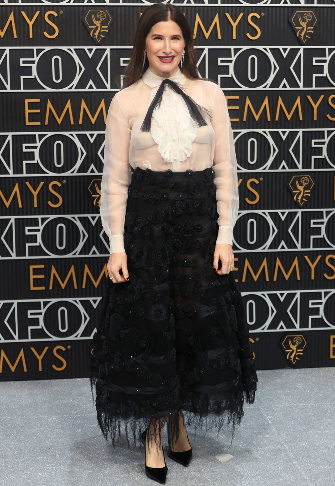 Kathryn Hahn lució joyas de Sophie Bille Brahe y un conjunto de cóctel Primavera-Verano 2019 de Dior Alta Costura, compuesto por camisa con pechera de organza marfil y falda negra bordada.