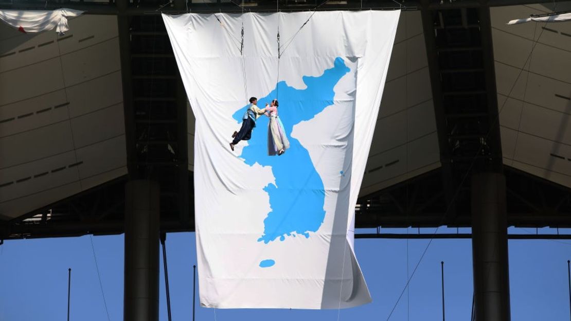 Artistas surcoreanos actúan frente a una enorme bandera de unificación en el estadio de la Copa Mundial de Seúl el 11 de agosto de 2018 en Corea del Sur.