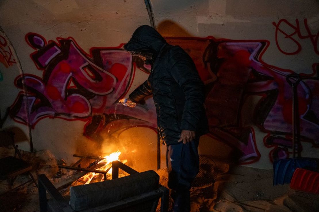 Un migrante extingue una fogata mientras el grupo que se había refugiado bajo el puente se prepara para ir a un refugio improvisado en una iglesia. Crédito: Evelio Contreras/CNN