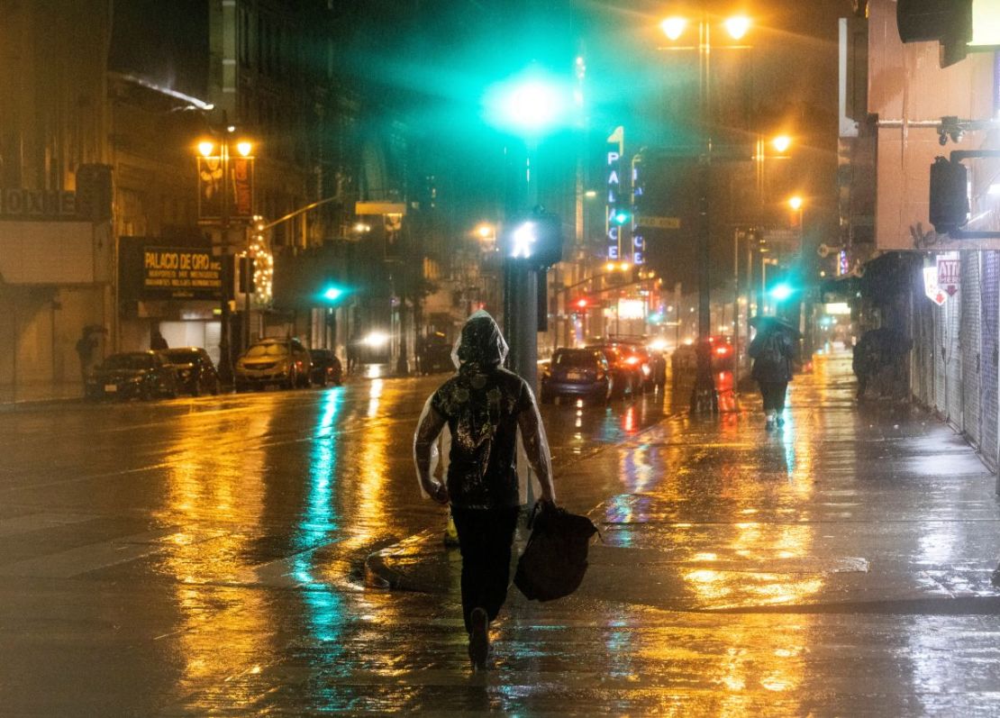 Personas caminan el domingo durante las fuertes lluvias en el centro de Los Ángeles.