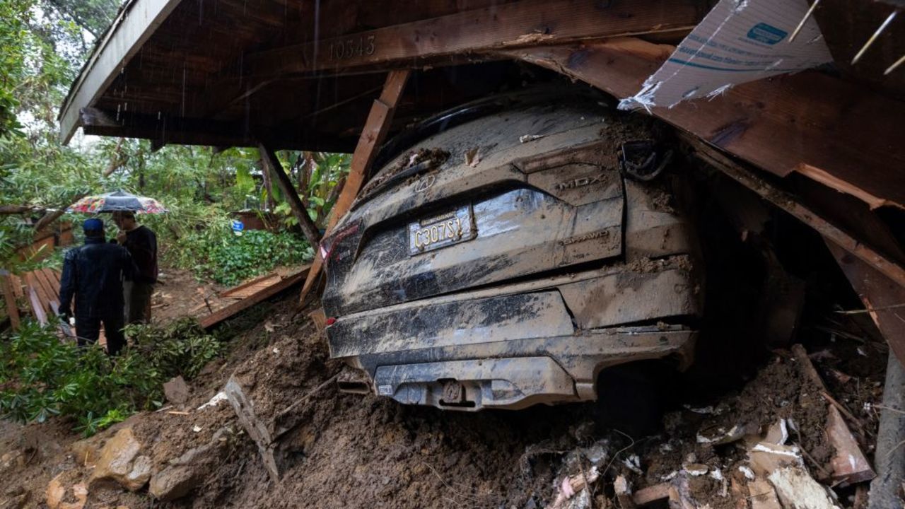 TOPSHOT - A car remains in the wreckage after a house and garage were destroyed by a landslide as a historic atmospheric river storm inundates the Hollywood Hills area of Los Angeles, California, on February 6, 2024. A powerful storm lashing California has left at least three people dead and caused devastating mudslides and flooding, after dumping months' worth of rain in a single day. (Photo by DAVID MCNEW / AFP)