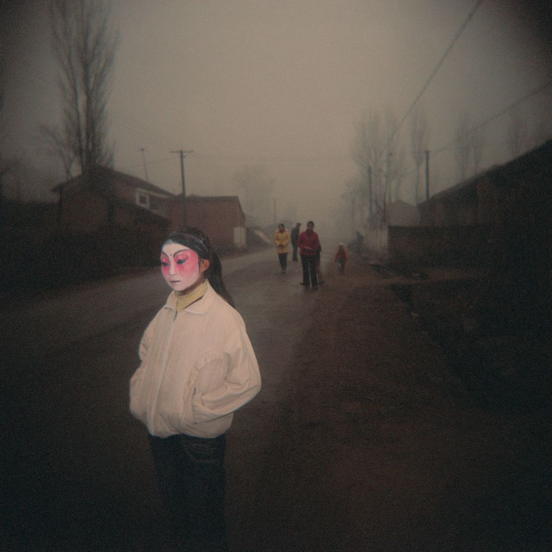 Una niña espera para ponerse el traje completo antes de las festividades en el pueblo de Huanghuayu, provincia de Shaanxi.