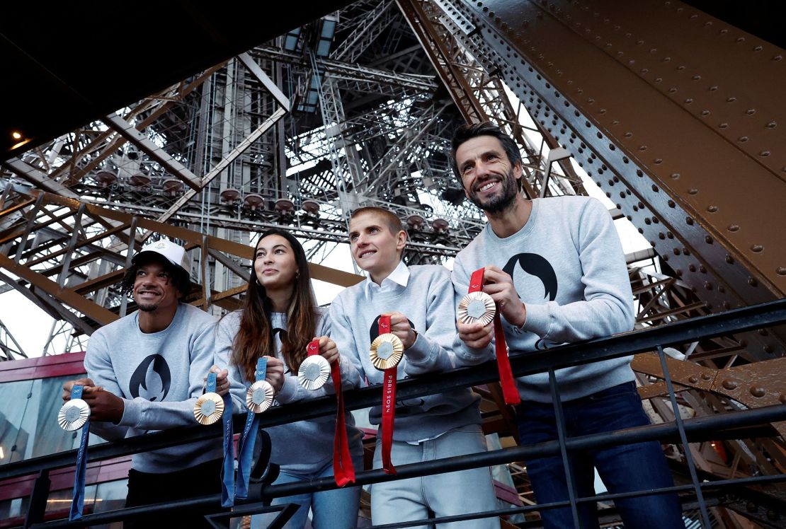 De derecha a izquierda: Tony Estanguet, presidente del comité organizador de los Juegos Olímpicos de París 2024, en la Torre Eiffel, con la ciclista francesa Marie Patouillet, la esgrimista Sara Balzer y el atleta Arnaud Assoumani sosteniendo medallas de los Juegos Olímpicos y Paralímpicos.