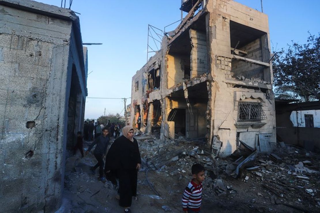 Palestinos caminan junto a un edificio residencial destruido en un ataque israelí en Rafah, Franja de Gaza, 11 de febrero de 2024.