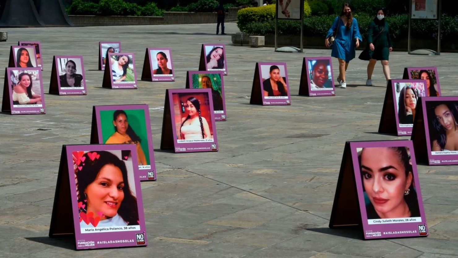 Dos mujeres caminan entre los carteles con las fotos de las víctimas de femicidios, en el marco de una campaña en el Día de la Eliminación de la Violencia hacia las Mujers en Medellí, Colombia, el 23 de noviembre de 2020.