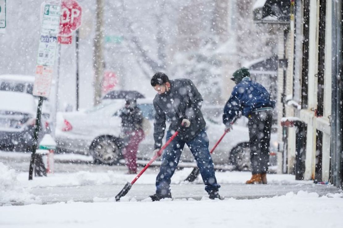 La gente limpia una acera durante una tormenta de nieve invernal en Filadelfia.