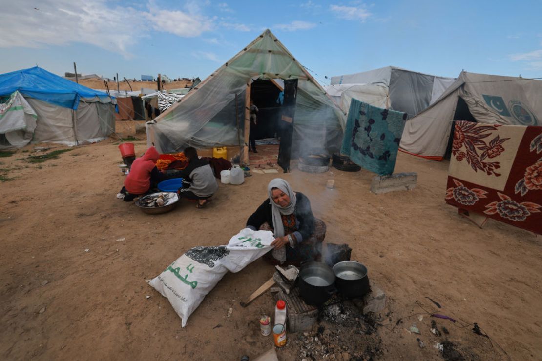 Una mujer palestina que huyó de Khan Younis prepara comida para su familia en un campamento establecido para personas desplazadas del norte en la región de Rafah, en el sur de la Franja de Gaza, el 15 de febrero de 2024.