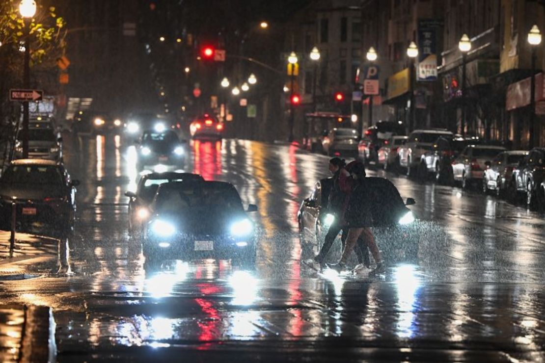 Personas cruzan la calle bajo la lluvia en San Francisco el 18 de febrero de 2024.