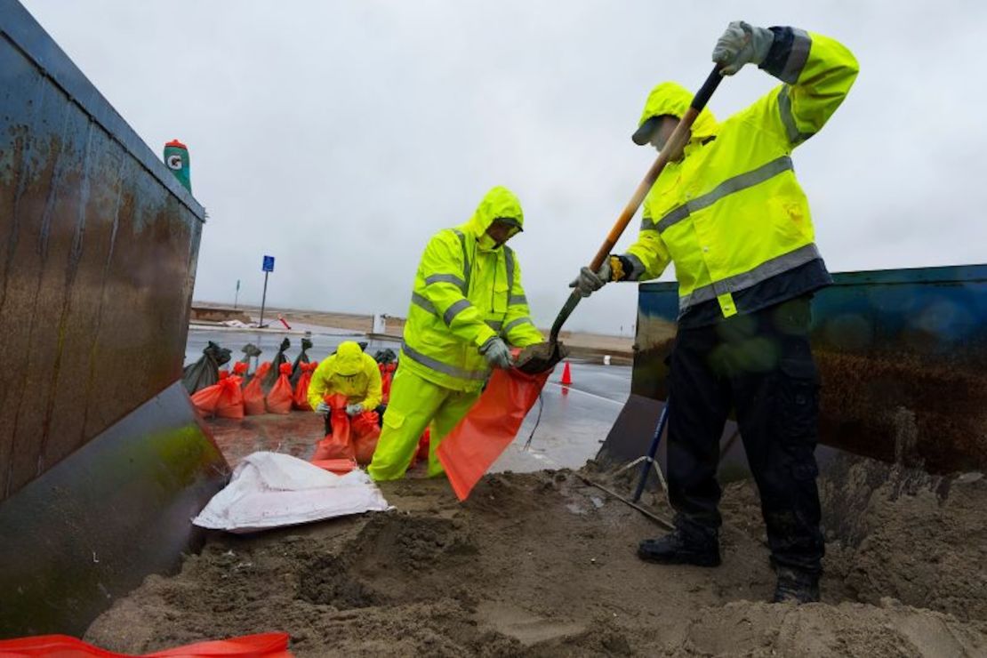 Los salvavidas de Oceanside del Departamento de Bomberos de Long Beach cargan cientos de sacos de arena para proteger las casas en la Península en Long Beach, California, el lunes 19 de febrero.