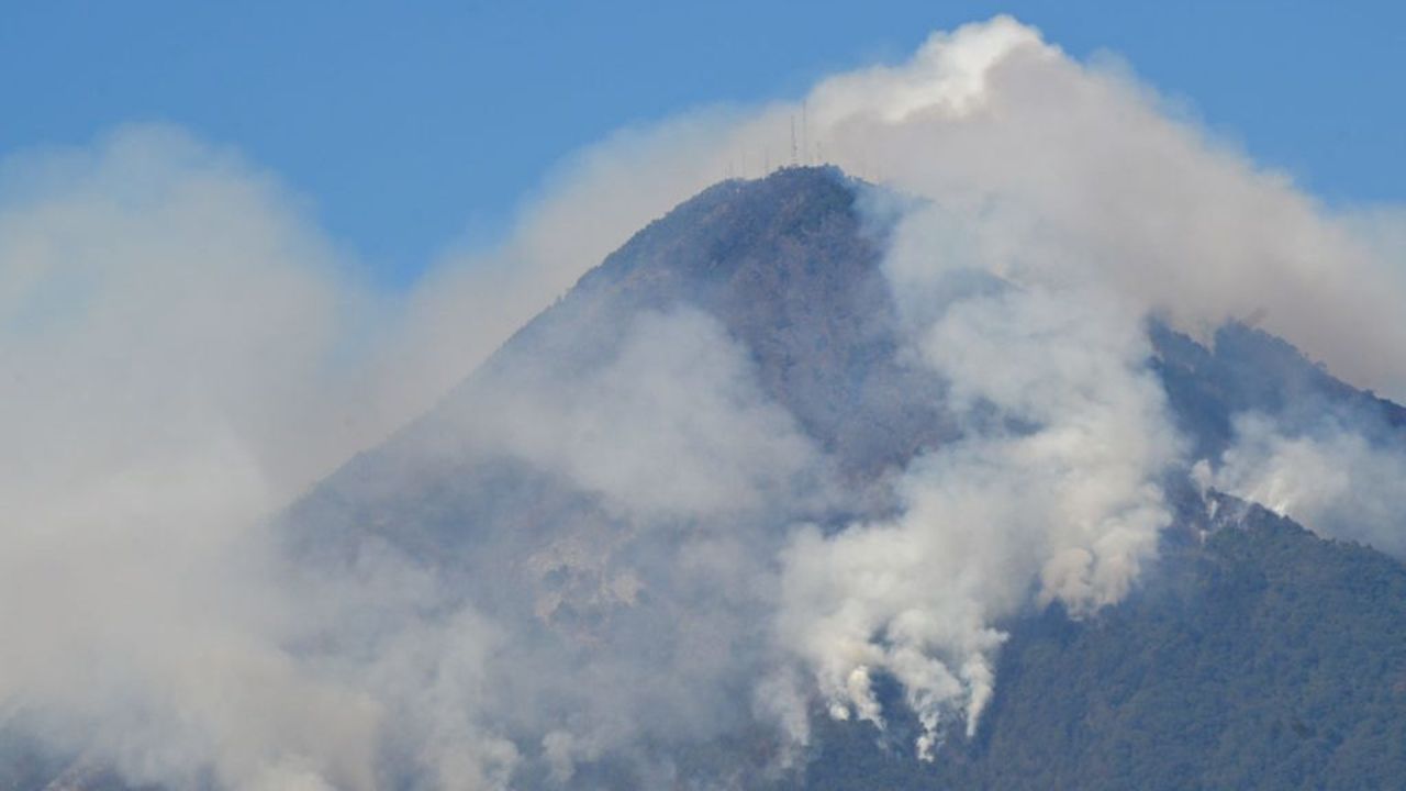 Smoke billows from wildfires on the slopes of the Agua Volcano, as seen from Villa Nueva, Guatemala, on February 22, 2024. A voracious forest fire is raging on the slopes of the dormant Agua volcano, near the capital of Guatemala, with no casualties or evacuations reported so far. (Photo by Johan ORDÓÑEZ / AFP)