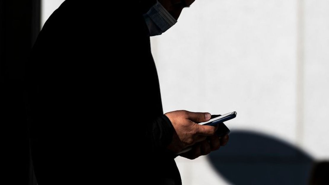 Una usuario de un teléfono inteligente se para frente a una tienda en Walnut Creek, California, en enero de 2022.