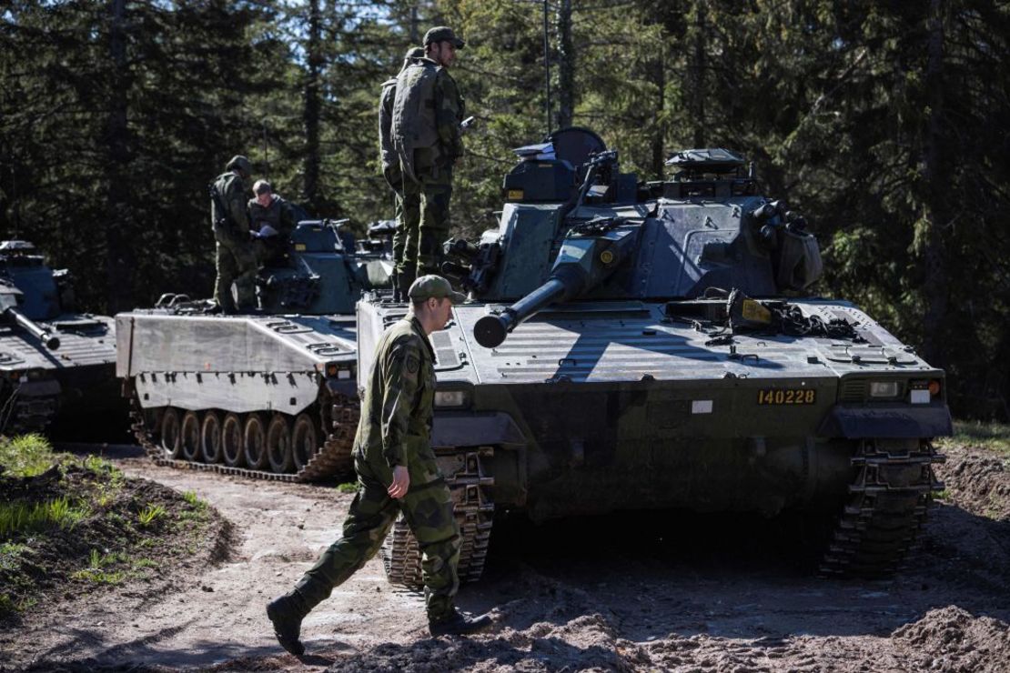 Un soldado del Regimiento P18 Gotland del ejército de Suecia camina junto a vehículos blindados durante un ejercicio cerca de Visby, en la isla sueca de Gotland, el 17 de mayo de 2022.