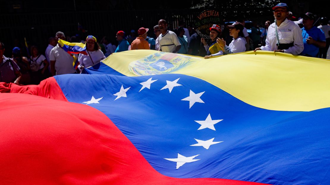 Simpatizantes de la candidata presidencial María Corina Machado del Partido Vente Venezuela sostienen y ondean una bandera venezolana gigante durante una manifestación en la Plaza Francia de Altamira el 23 de enero de 2024 en Caracas, Venezuela. Crédito: Javier Campos/Getty Images