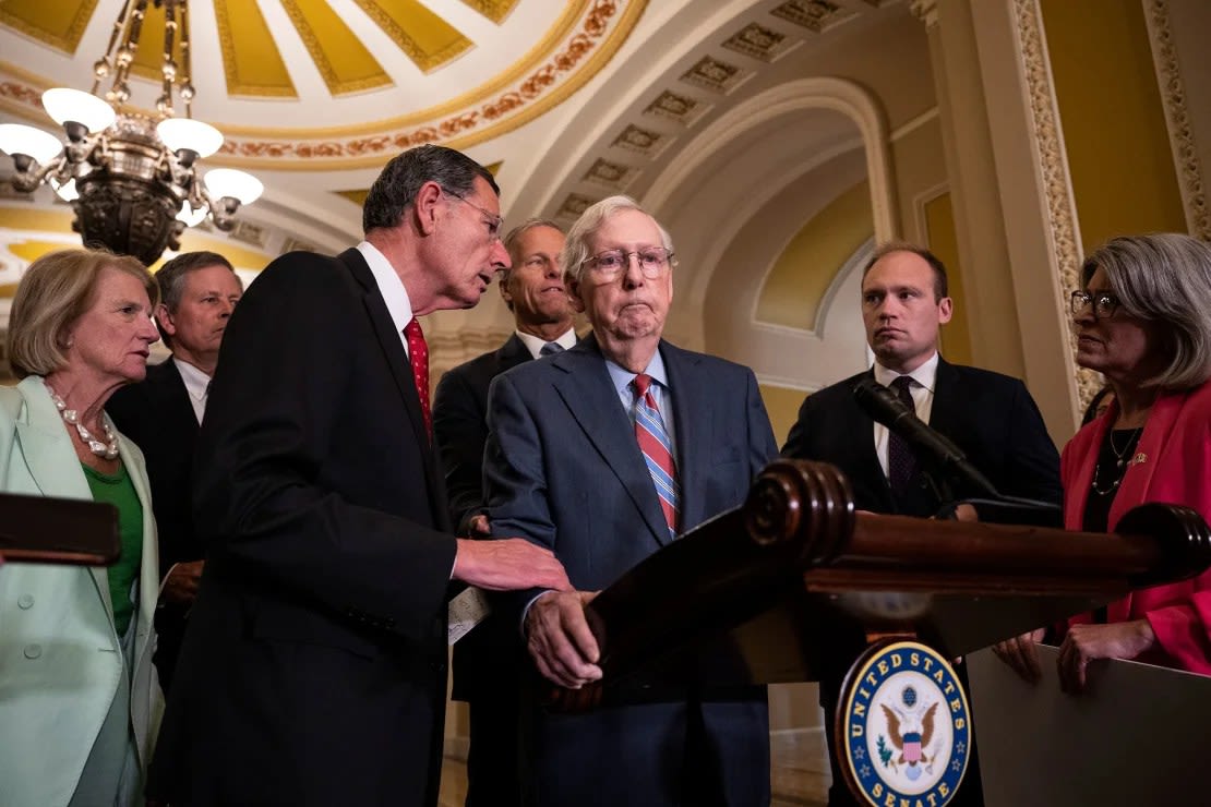 El senador John Barrasso se acerca para ayudar a McConnell después de que se quedara paralizado y dejara de hablar durante una conferencia de prensa en el Capitolio en julio de 2023. Un asistente sacó a McConnell de la conferencia de prensa y lo llevó hacia su oficina. Regresó unos minutos más tarde y continuó. Drew Angerer/Getty Images