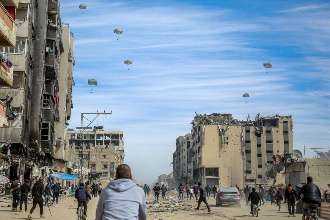 Palestinos corren por una calle mientras cae la ayuda humanitaria lanzada desde el aire por Jordania en la ciudad de Gaza el 1 de marzo, en medio del conflicto entre Israel y el Hamas.