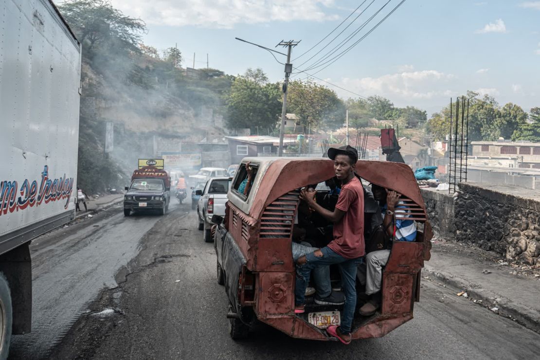 Un hombre se para en la parte trasera de un camión mientras cruza hacia el vecindario Delmas 6.