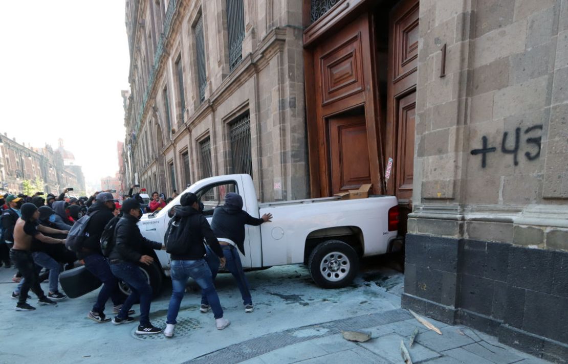 Manifestantes empujan una camioneta para derribar la puerta del palacio presidencial en la Ciudad de México el 6 de marzo de 2024, durante una protesta por la desaparición de los 43 estudiantes de la escuela de formación docente de Ayotzinapa en 2014.