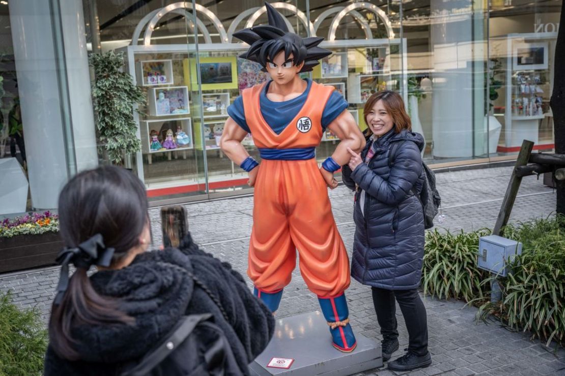 Una mujer se toma fotografías con una estatua del personaje de Dragon Ball "Son Goku" en Tokio el 8 de marzo de 2024.