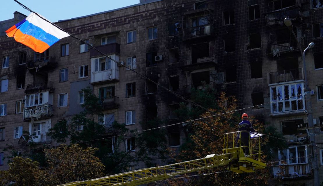 Una bandera rusa ondea en un cable frente a un edificio dañado en Mariupol el 25 de septiembre de 2022.