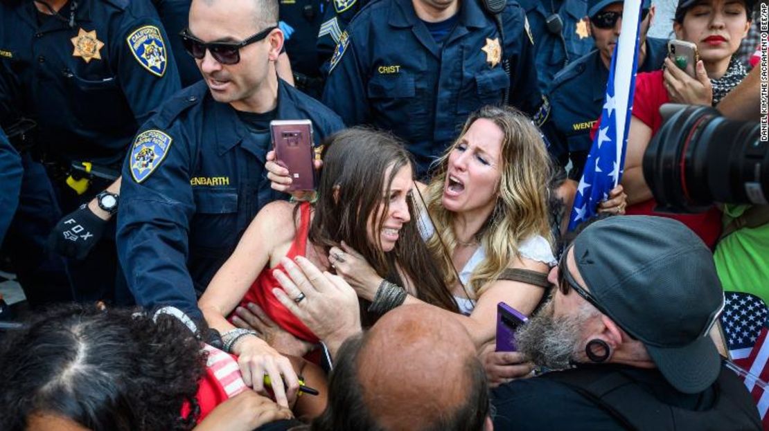 Heidi Muñoz Gleisner, en el centro a la izquierda, es retirada de una protesta en contra del confinamiento en California.