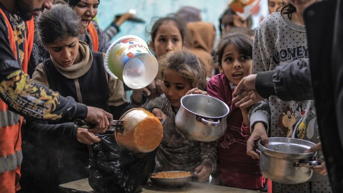 Palestinos desplazados se reúnen para recoger alimentos cocinados por voluntarios en Rafah el 9 de diciembre de 2023.