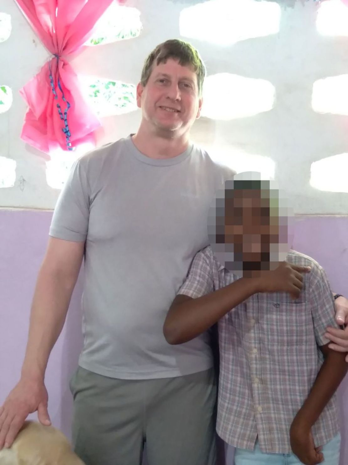 John Tennant se ve en una foto sin fecha con uno de los dos adolescentes que la pareja adoptó de Haití. CNN borró el rostro del niño para proteger su identidad.