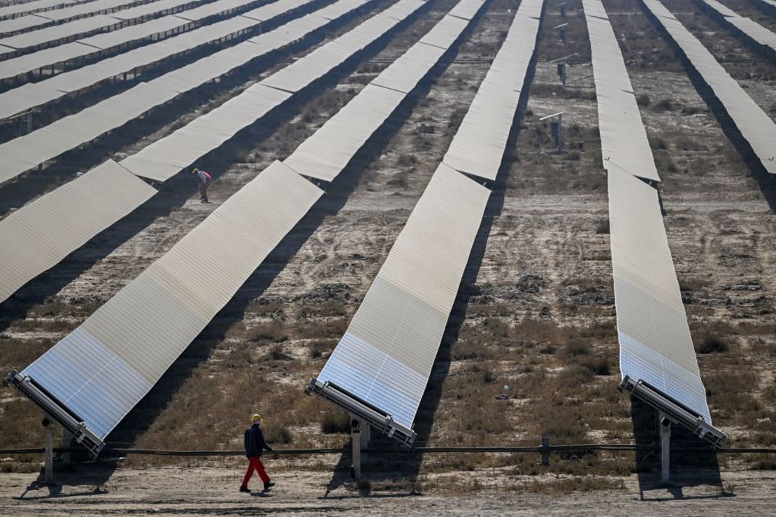 Un trabajador pasa junto a hileras de paneles solares en el Parque de Energías Renovables de Khavda. Crédito: Punit Paranjpe/AFP/Getty Images