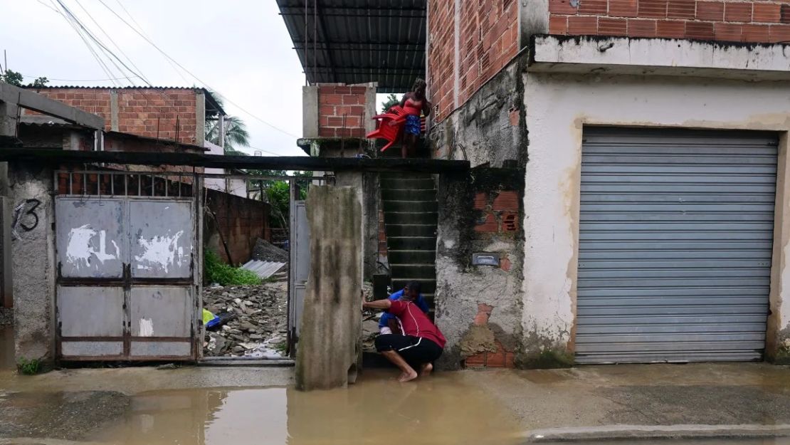 La gente intenta sacar el agua de su casa inundada después de una tormenta en las afueras de Río de Janeiro el domingo 24 de marzo. Pablo Porciuncula/AFP/Getty Images