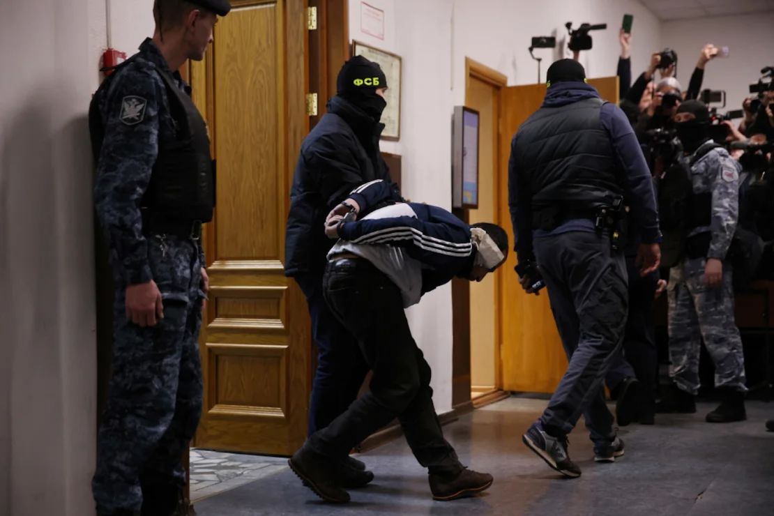 Un hombre sospechoso de participar en el ataque es escoltado por agentes de la ley rusos antes de su audiencia de detención previa al juicio en el Tribunal del Distrito de Basmanny, en Moscú, el 24 de marzo de 2024.