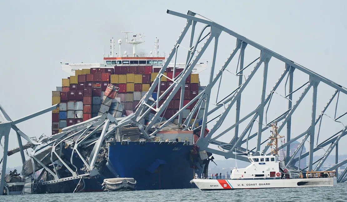 Un guardacostas pasa junto al carguero que derribó el puente Francis Scott Key en Baltimore.