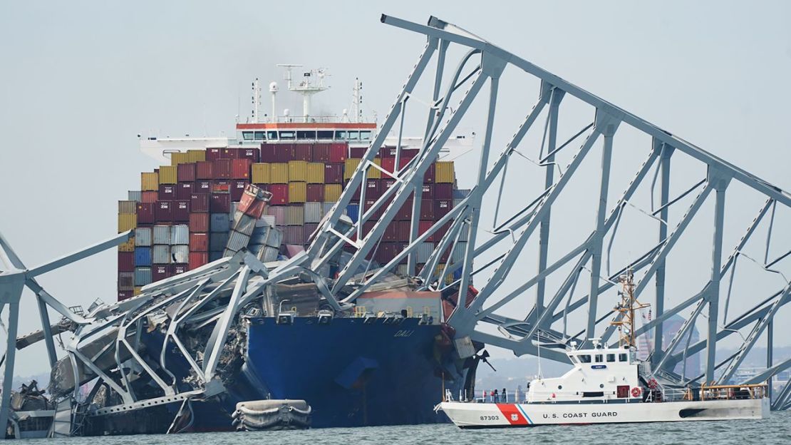 Un cortador de la Guardia Costera pasa por un buque de carga que está atascado bajo parte de la estructura del puente Francis Scott Key después de que el barco chocara contra el puente el martes 26 de marzo de 2024, en Baltimore, Maryland.