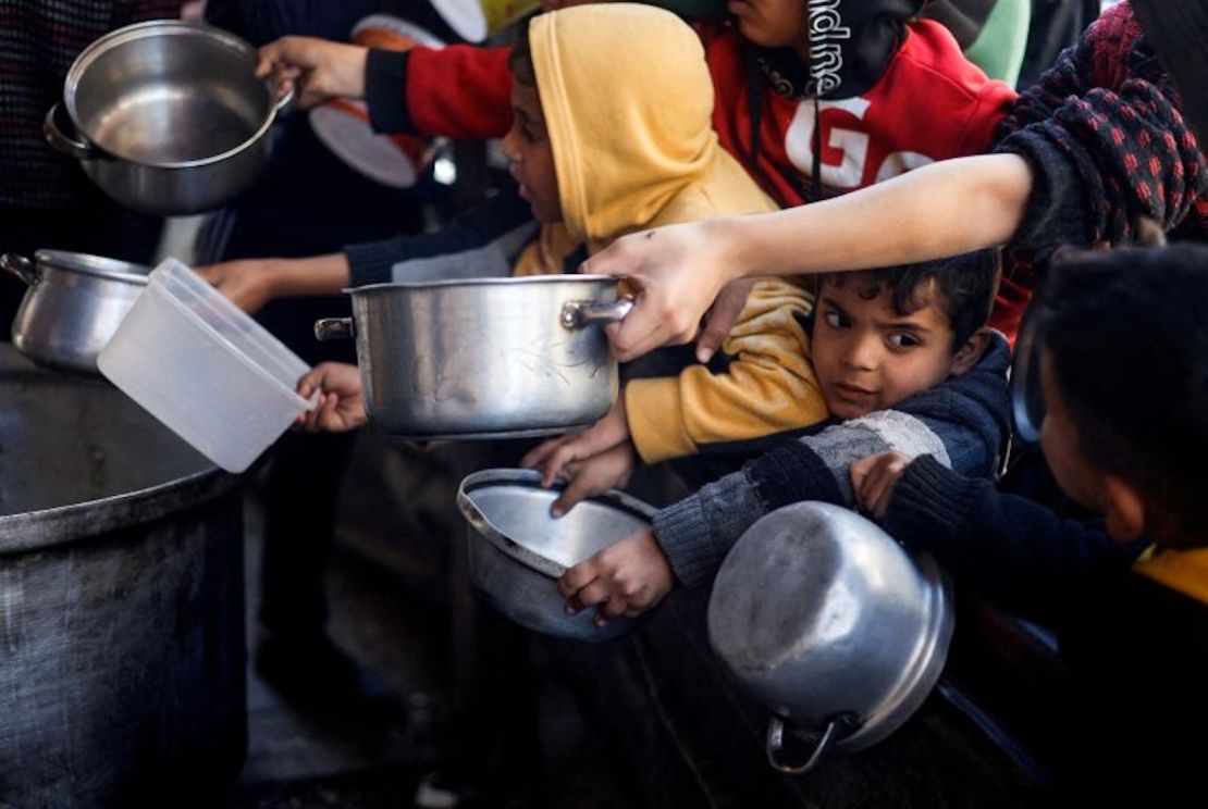 Niños palestinos en Rafah esperan para recibir alimentos distribuidos por una cocina de caridad en medio de una grave escasez de suministros alimentarios.