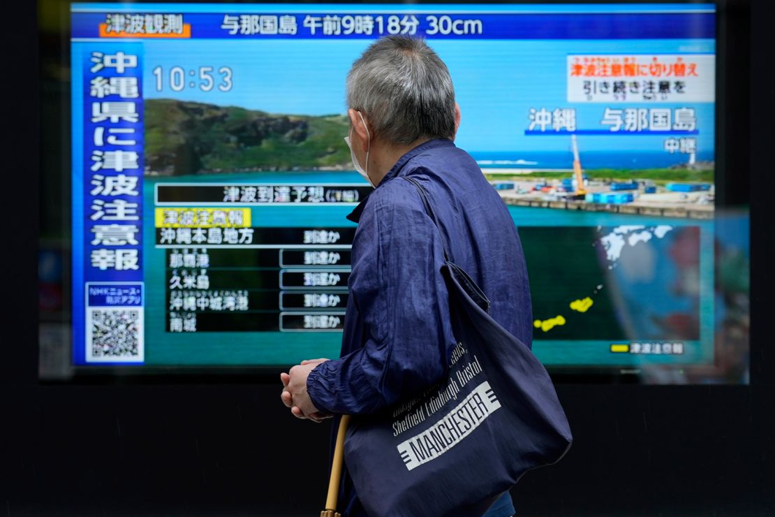 A man stands on a sidewalk in Tokyo to watch a television showing breaking news about the tsunami alert in Okinawa on April 3, 2024. The alert was later lifted.