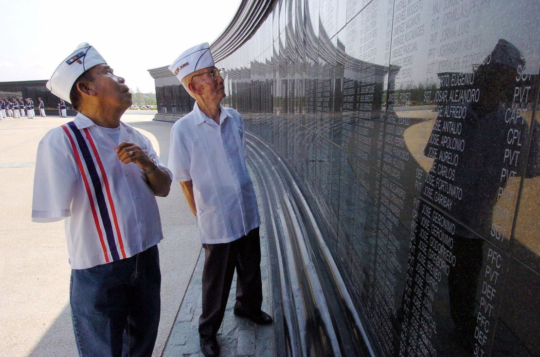 El veterano discapacitado filipino de la Segunda Guerra Mundial y sobreviviente de la marcha de la muerte Manuel Abrazado, de 80 años (izq.), y su camarada Emilio Aquino, de 86 (der.), observan los nombres de sus camaradas en el Santuario Nacional de Capas, en la provincia septentrional de Tarlac, el 6 de abril de 2004, durante una jornada conmemorativa de la caída de Bataán. Crédito: Romeo Gacad/AFP/Getty Images