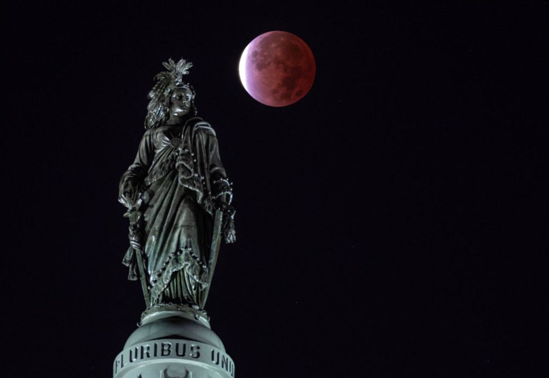 La Luna, con un eclipse lunar parcial, se ve detrás de la Estatua de la Libertad, en el Capitolio en la ciudad de Washington, la madrugada del 19 de noviembre de 2021.