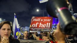 Familiares y partidarios de los rehenes israelíes retenidos en Gaza sostienen pancartas y ondean banderas israelíes durante una manifestación frente al Ministerio de Defensa en la ciudad costera israelí de Tel Aviv, el 6 de abril de 2024