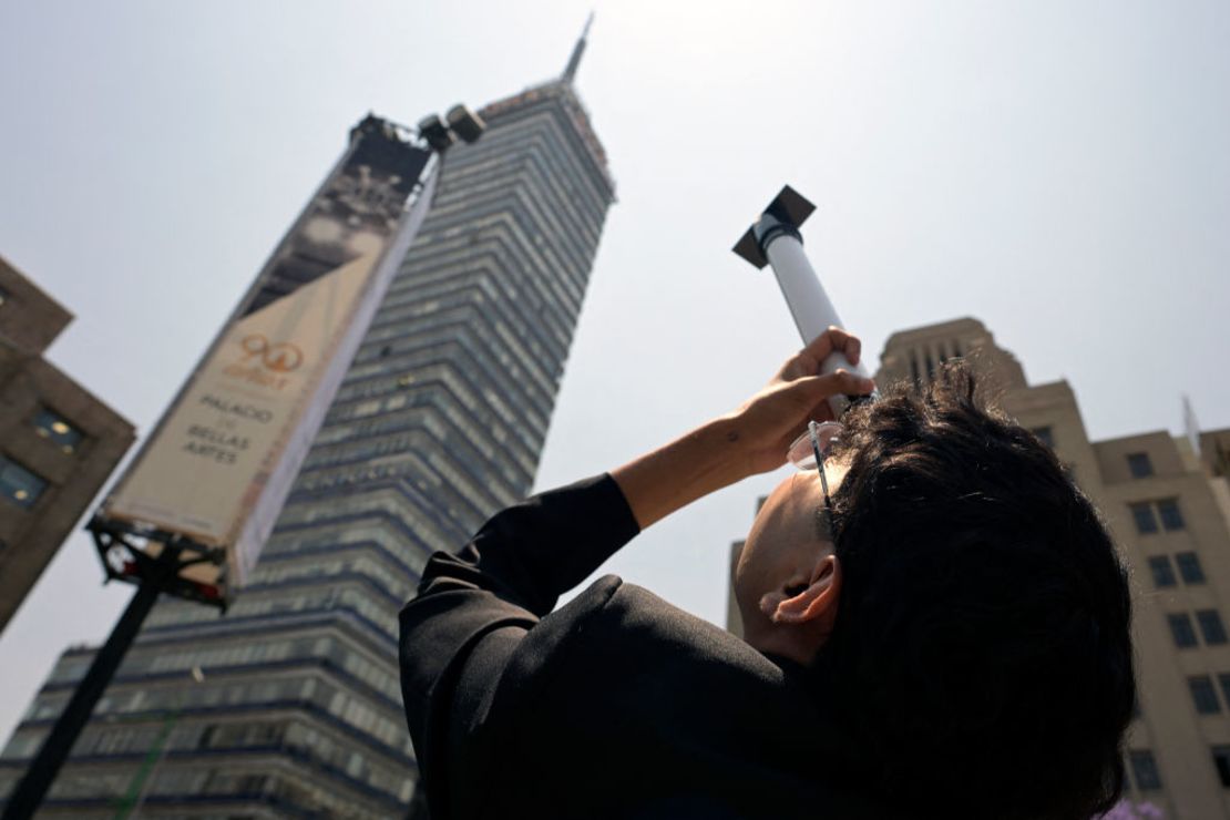 Un hombre mira hacia el cielo mientras la luna comienza a eclipsar parcialmente al sol frente al Palacio de Bellas Artes en la Ciudad de México el 8 de abril de 2024.