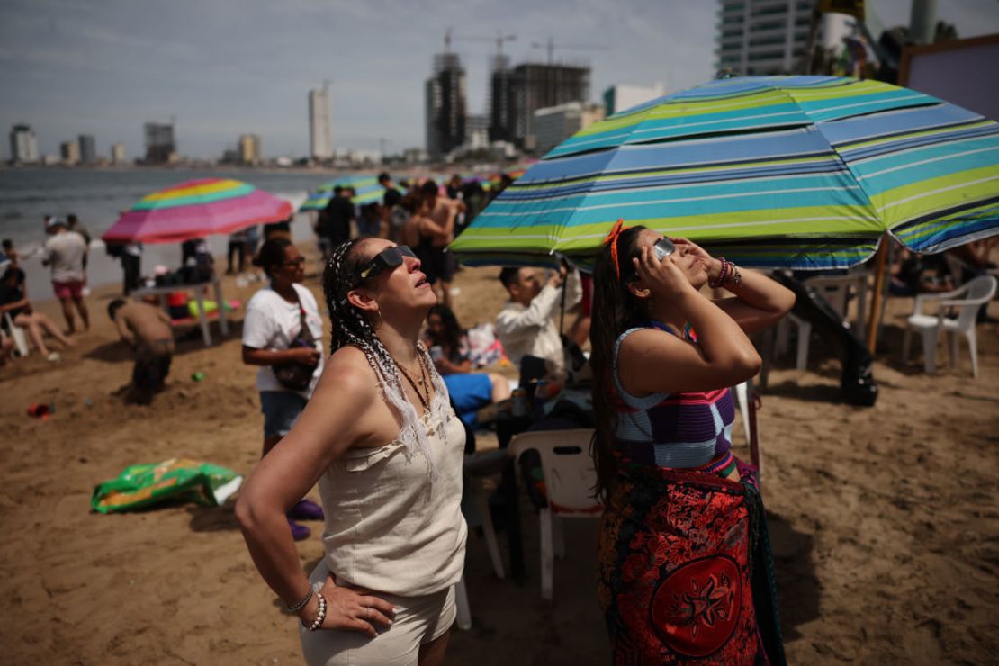 Personas en las playas de Mazatlán, México, observan el eclipse solar total.