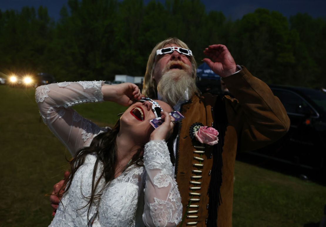 Unos novios contemplan el eclipse solar en medio de un cielo oscurecido tras casarse en una boda multitudinaria en el festival Total Eclipse of the Heart el 8 de abril de 2024 en Russellville, Arkansas.