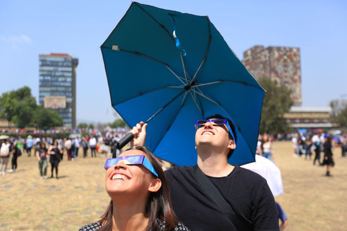 Una pareja mira al cielo con lentes especiales durante el eclipse solar en "Las Islas" de la UNAM en la Ciudad de México.