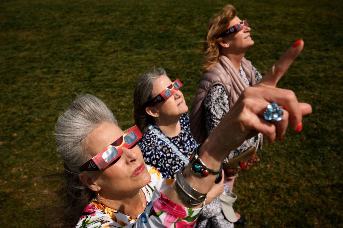 Lori Darnell de Lincoln, California, Julie Plemmons y Denise Lonngren, ambas de San Diego, California, observan el eclipse solar cerca de la base del Monumento a Washington el 8 de abril de 2024 en la ciudad de Washington.