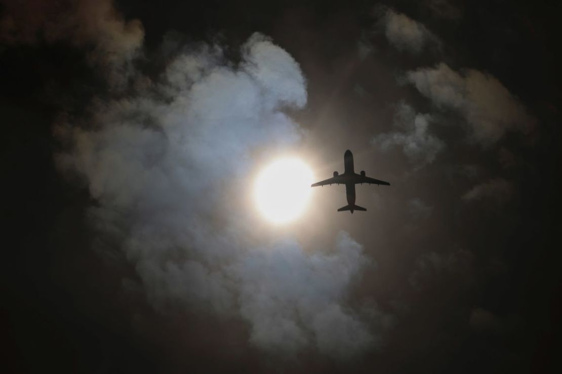 Un avión pasa por encima mientras se observa un eclipse parcial en el barrio de Queens, en Nueva York.