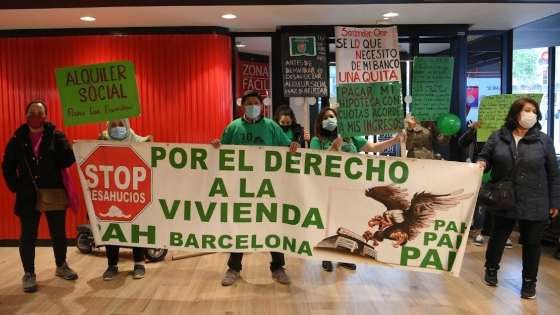 Activistas de la Plataforma Antidesahucios de Afectados por la Hipoteca (PAH) sostienen una pancarta en la que se lee "Por el derecho a la vivienda en Barcelona" durante una protesta en el interior de un espacio de coworking del Banco Santander en Barcelona el 28 de abril de 2021.