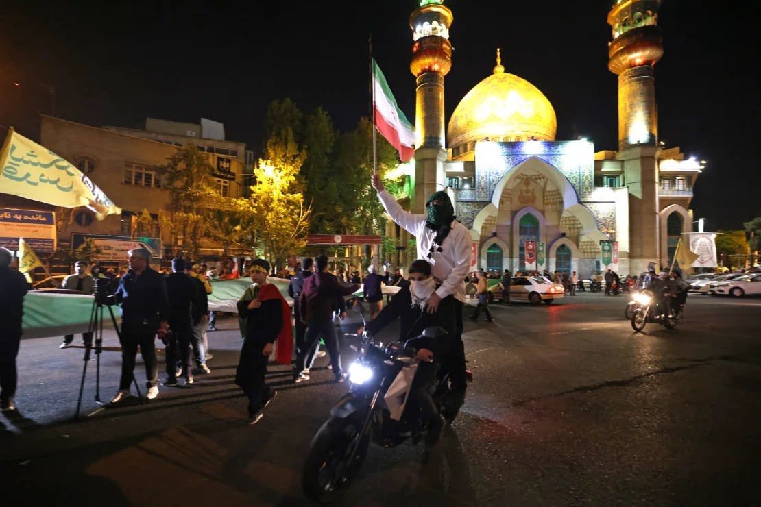 Manifestantes ondean la bandera de Irán mientras se reúnen en la Plaza de Palestina en Teherán el 14 de abril de 2024, después de que Irán lanzara un ataque con drones y misiles contra Israel.