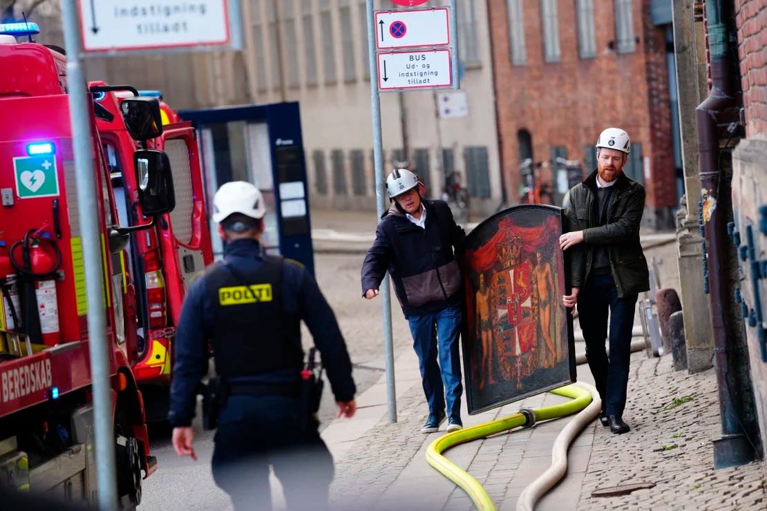 La gente rescata un cuadro de la antigua bolsa de valores después de que se produjera un violento incendio el martes por la mañana.