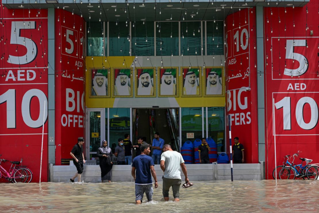 Hombres cruzan una calle inundada tras las fuertes lluvias en Sharjah, en los EAU, el 17 de abril de 2024.