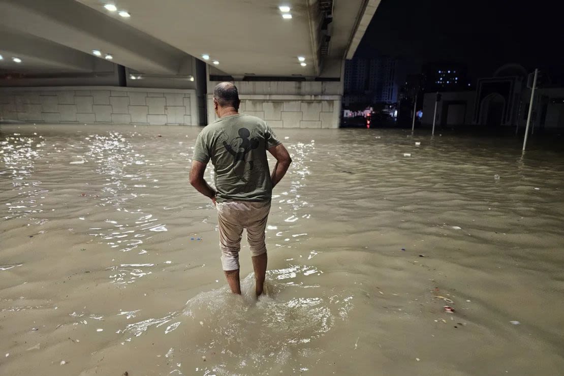 Varias personas atraviesan una calle sumergida bajo un puente tras las fuertes lluvias registradas el martes en los Emiratos Árabes Unidos.